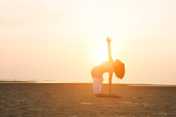pregnant mother performing yoga on beach - Zdjęcie, obraz
