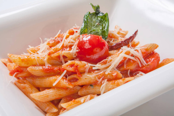 Penne pasta with tomato sauce sprinkled with Parmesan cheese in a deep white plate - Foto, Imagem