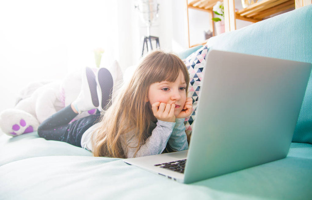 Cute little girl using laptop on sofa at home - Fotografie, Obrázek