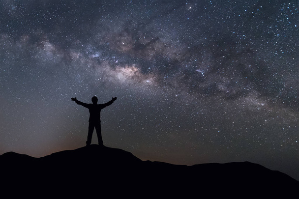Пейзаж Млечного пути. Силуэт счастливого человека, стоящего на вершине горы с ночным небом и яркой звездой на фоне
.  - Фото, изображение