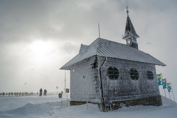 Śnieg i pochmurny widok kaplicy w górach w pobliżu Zell am patrz, A - Zdjęcie, obraz