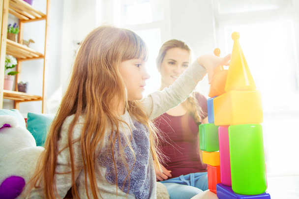 Söpö pieni tyttö ja hänen äitinsä leikkivät lohkojen kanssa yhdessä, perhe kotona
 - Valokuva, kuva