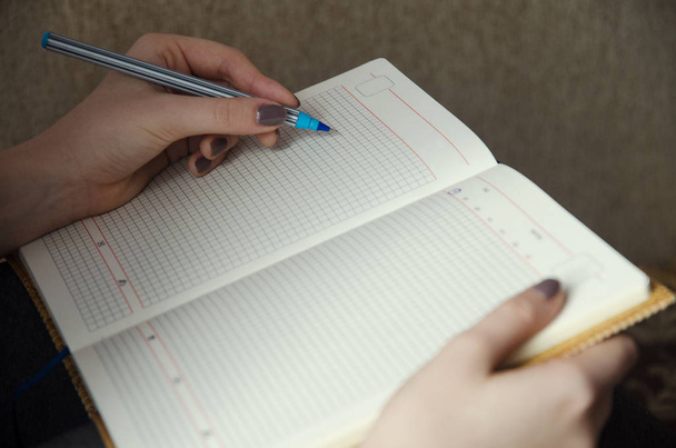 Τα χέρια της μια κοπέλα που γράφει σε ένα σημειωματάριο - Φωτογραφία, εικόνα