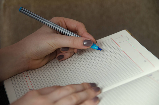 Mãos de uma menina que escreve em um caderno
 - Foto, Imagem