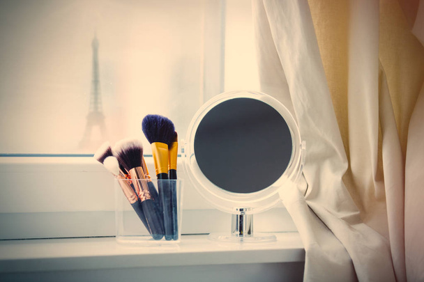 pinceaux de maquillage et miroir sur le rebord de la fenêtre
 - Photo, image