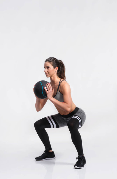 Fitness woman in sports clothing holding medicine ball, studio s - Zdjęcie, obraz