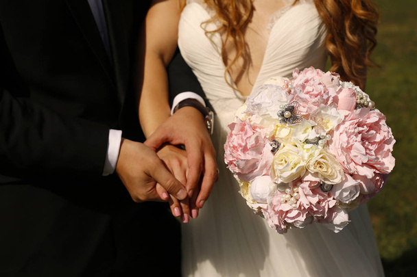 Bridal couple holding hands and wedding bouquet - Фото, зображення