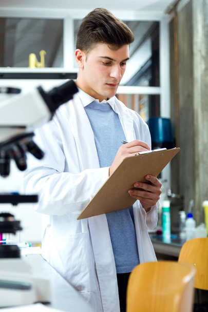 Handsome young man working in laboratory. - Фото, изображение