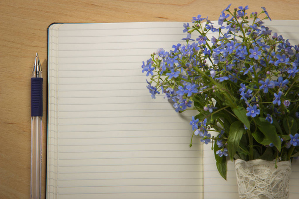 A bouquet of flowers forget-me, notebook and pen on the wooden t - Foto, Bild