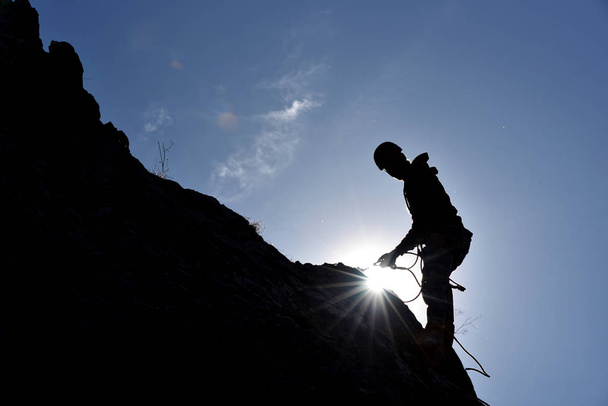 Σιλουέτα του ένα βράχο ορειβάτης που κρέμονται στον τοίχο  - Φωτογραφία, εικόνα