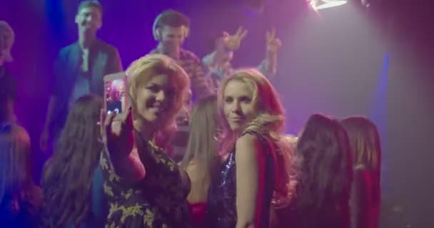 Freundinnen fotografieren sich mit dem Handy, während sie Musik im Nachtclub genießen - Filmmaterial, Video