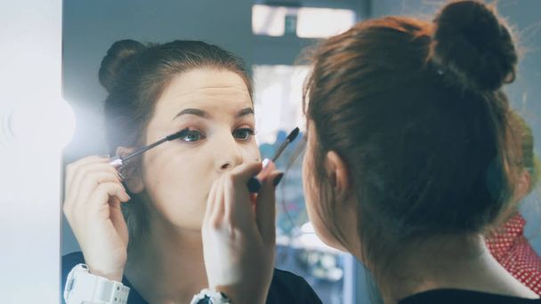 Woman applying black mascara on eyelashes with makeup brush. Young beautiful lady applying mascara makeup on eyes - Фото, изображение