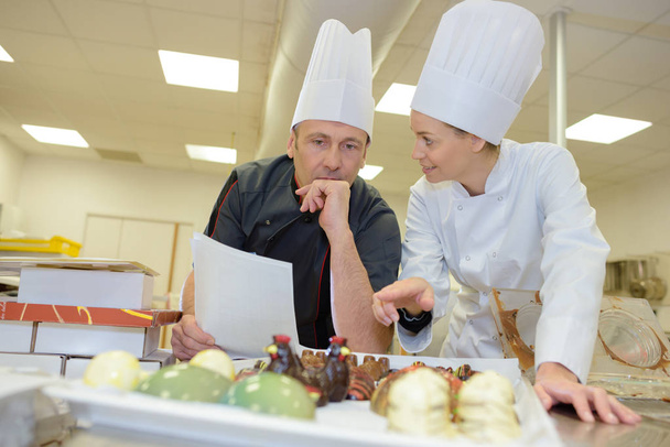 portrait of hospitable chef with young smiling female helper - Foto, afbeelding