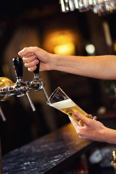Barman leje świeże piwo w pubie, ręka barman piwo stuknięciu nalewać piwo lager, piwo z kranu, wypełnienie ze szkła z piwa, świeże piwo, pub. Bar.Restaurant.European bar. Amerykański bar. - Zdjęcie, obraz
