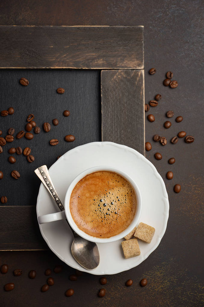 暗い背景にコーヒー豆と新鮮なコーヒーのカップ - 写真・画像