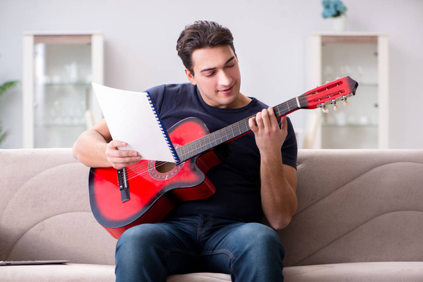 Young man practicing playing guitar at home - Photo, Image