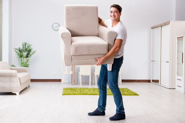 Young man moving furniture at home - Foto, Imagen