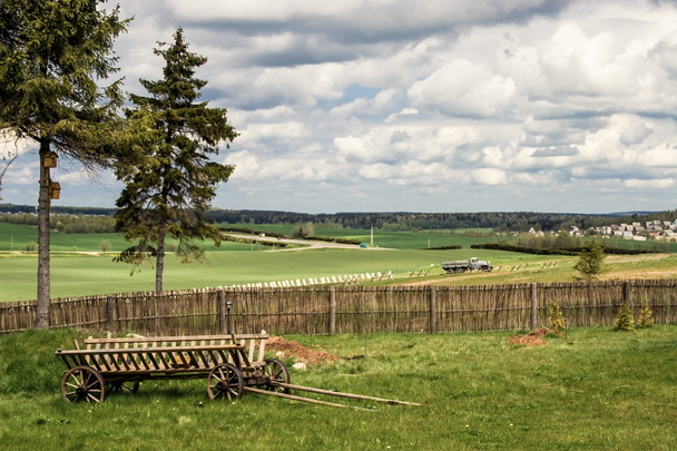 Paysage rural avec cour de campagne, clôture et vieux chariot en bois
 - Photo, image