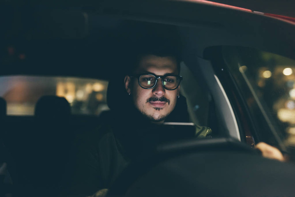 man met smartphone in auto 's nachts - Foto, afbeelding