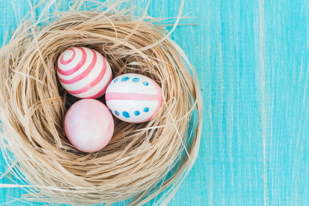 Colorful Easter Eggs on the rustic wooden background with nest. Selective focus. Top view. - Zdjęcie, obraz