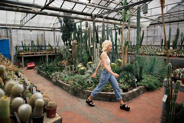 Beautiful blonde woman walking in cactus and succulent plants  - Photo, image