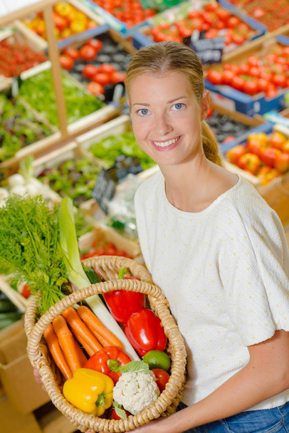 Lady holding wicker basket of vegetables - 写真・画像