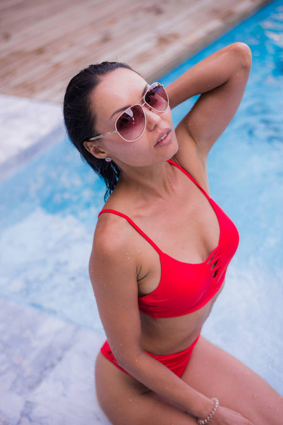 Passar o dia quente de verão junto à piscina. Mulher bonita em biquíni vermelho relaxante na piscina
. - Foto, Imagem