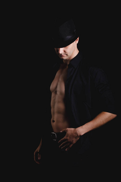hattupäinen mies mustalla taustalla
 - Valokuva, kuva