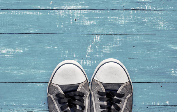 Блакитні чоловічі старі шорсткі кросівки на синій дерев'яній поверхні
 - Фото, зображення