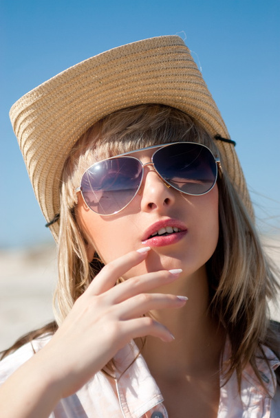 Retrato de mulher loira em chapéu de cowboy e óculos de sol em uma praia de areia
 - Foto, Imagem