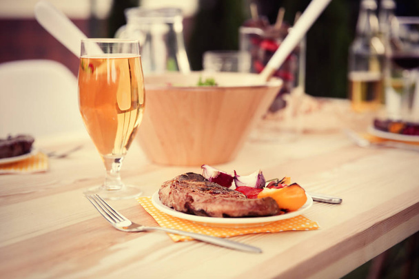 Glass of beer and plate with grilled meat  - Foto, afbeelding
