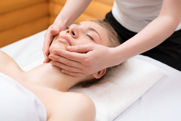 Young pretty woman enjoying face massage procedure - Φωτογραφία, εικόνα