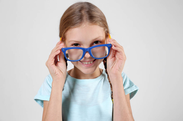 Little girl with spectacles on light background - Foto, afbeelding