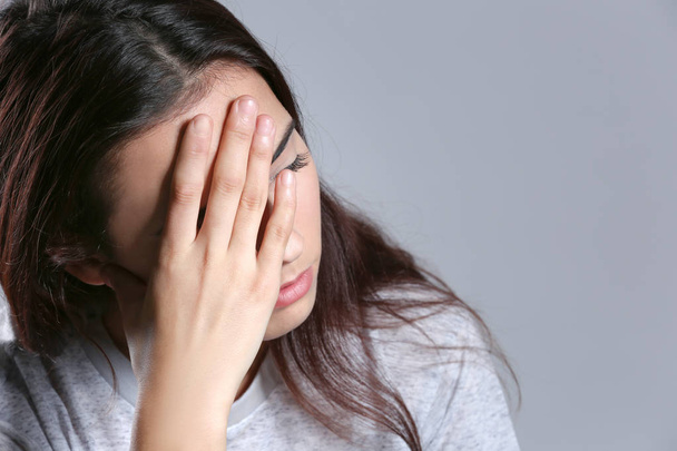 Young woman suffering from headache on color background, closeup - 写真・画像