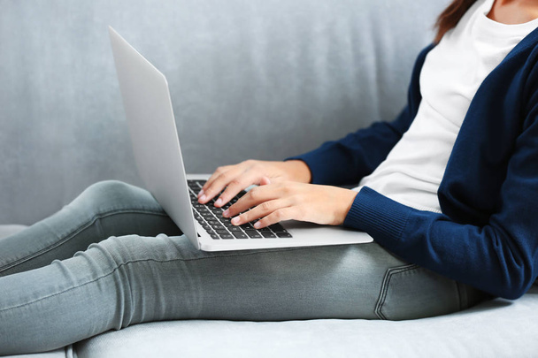 Cute girl sitting on sofa with laptop - Фото, изображение