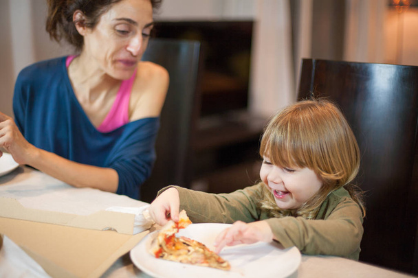 lapsi nauraa syöminen pizza äidin kanssa
 - Valokuva, kuva