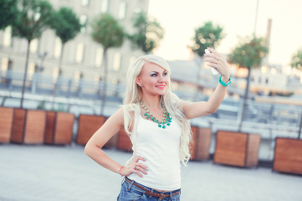 веселая молодая женщина ходит и делает селфи на смартфоне
  - Фото, изображение