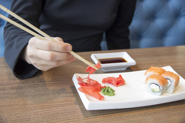 female hand takes ginger next to sushi roll - Foto, immagini