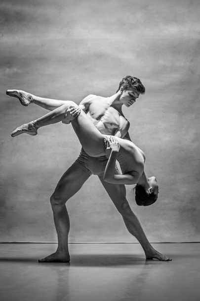 Couple of ballet dancers posing over gray background - 写真・画像