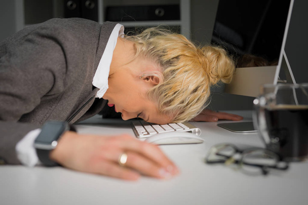 オフィスのコンピューターのキーボードで寝ている女性 - 写真・画像