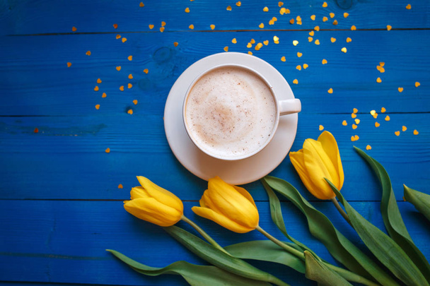 Coffee mug with yellow tulip flowers and notes good morning on blue rustic table - Valokuva, kuva