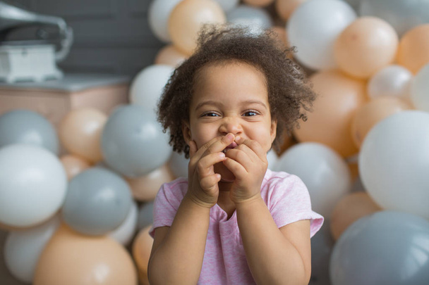 Portrait of Black little girl laughing on colorful balloons background - Foto, Imagen