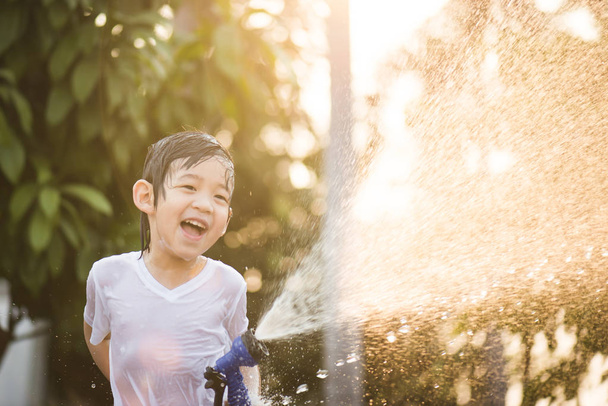 asiático chico tiene divertido jugando en agua
 - Foto, Imagen