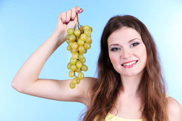 Beautiful woman with grape on blue background - Foto, Imagen