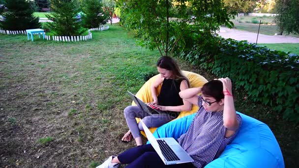 Női értékesítési vezetők csinálni nem van ideje, hogy minden munka és gyorsan típusa a számítógép billentyűzet ül a parkban a szabadban a puha székek nappali. - Felvétel, videó