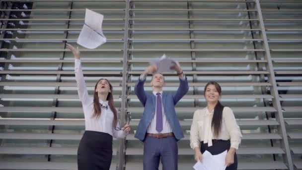 Trois personnes confiantes Entrepreneurs Scatter Paper et se réjouir Fin de la journée de travail et rire près du centre d'affaires En plein air dans des couleurs neutres
. - Séquence, vidéo