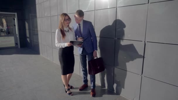 Pohledný podnikatel hovoří s Lady Business a dokumenty v rukou na pozadí z obchodního centra v neutrálních barvách. - Záběry, video