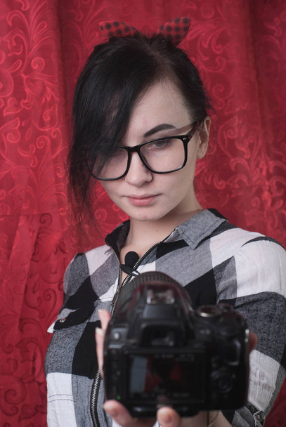 Μια νεαρή γυναίκα blogger ο ίδιος πυροβολεί για φωτογραφική μηχανή, όμορφη μελαχρινή σε ποτήρια, lifestyle vlog - Φωτογραφία, εικόνα