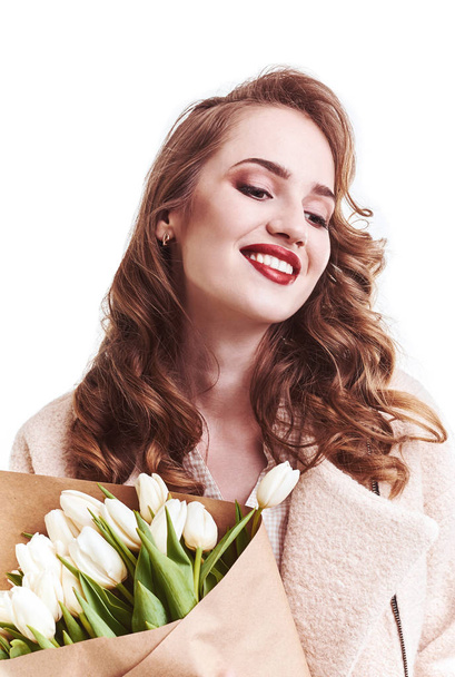 Beautiful girl in a coat with flowers tulips in hands on a light background - Fotoğraf, Görsel