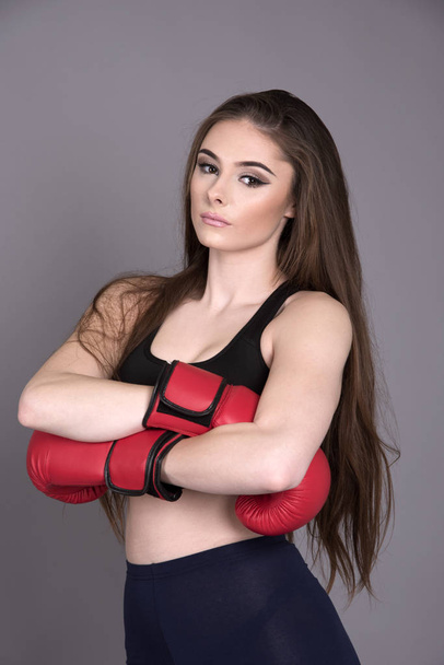 Fiatal női ökölvívó piros boksz-kesztyűket visel - Fotó, kép